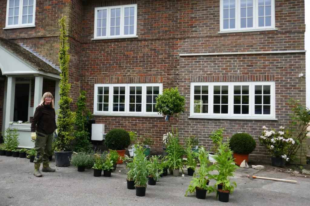 Michaela Day standing outside a large house whilst undertaking a planting.