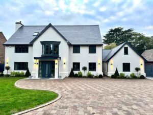 Large white new build house with border and curb-side garden design.